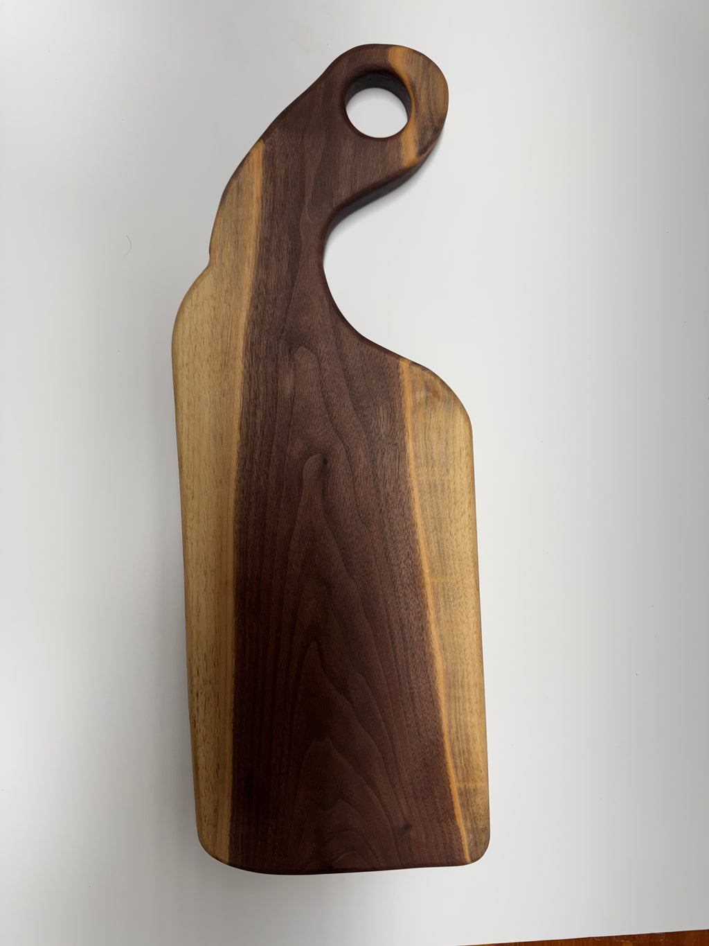 Handcrafted walnut serving board with curved handle - top view