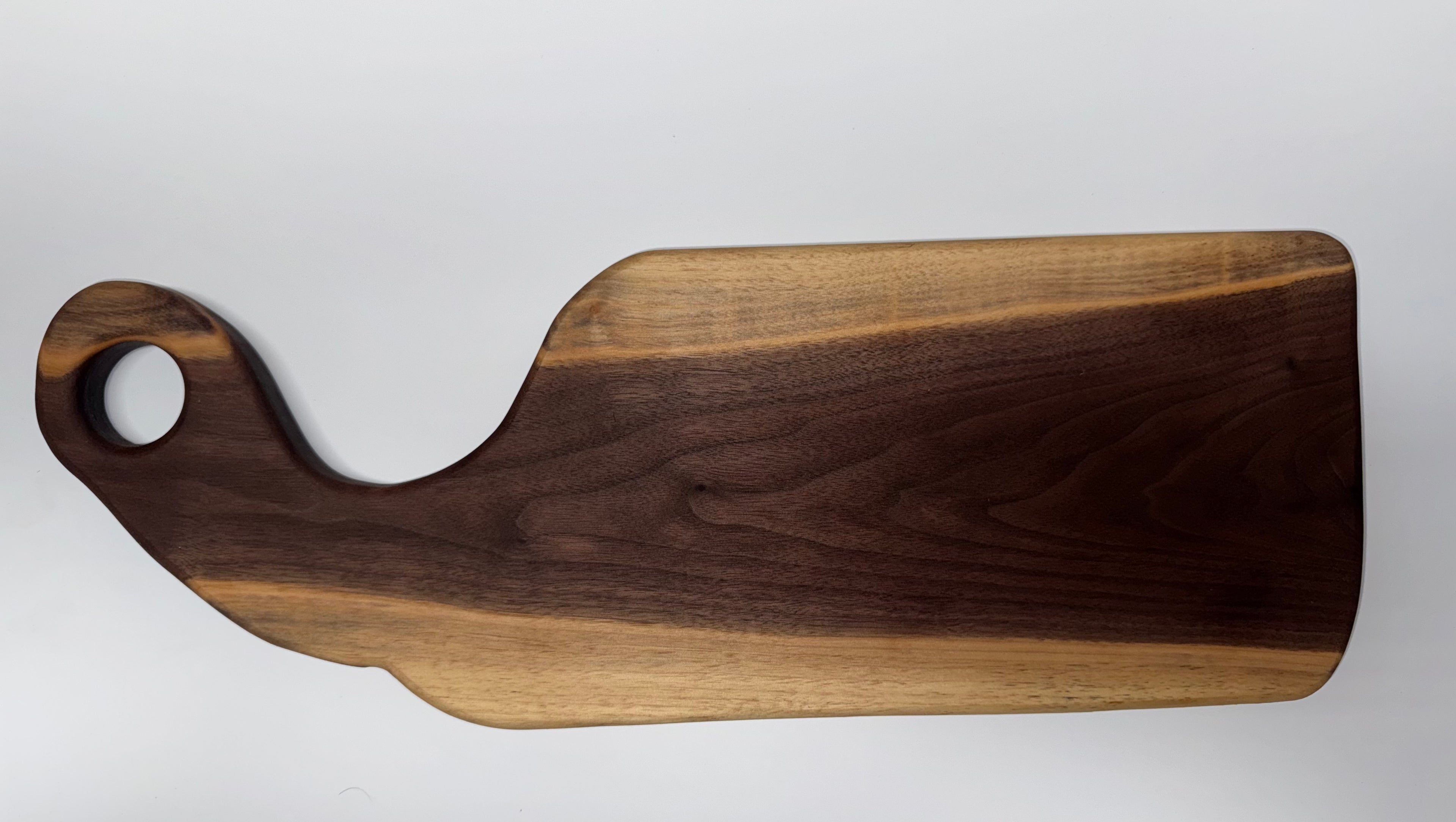 Handcrafted walnut serving board with curved handle - side view