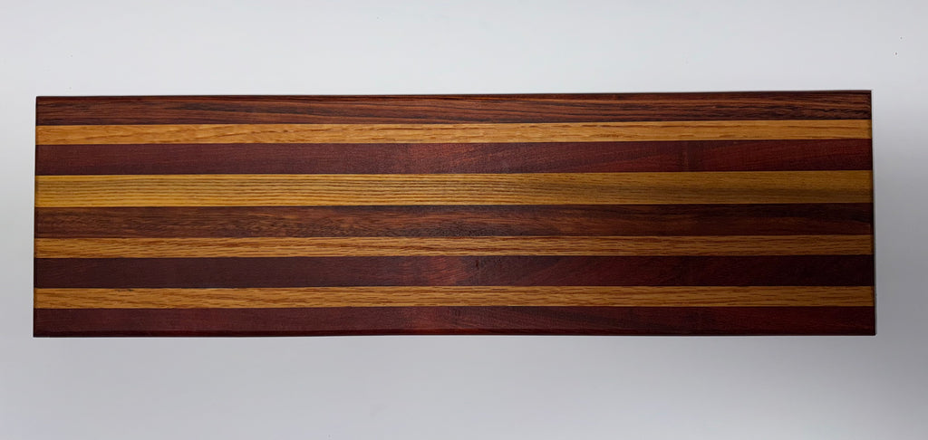 Striped hardwood cutting board with alternating purpleheart, oak, and walnut strips - top view