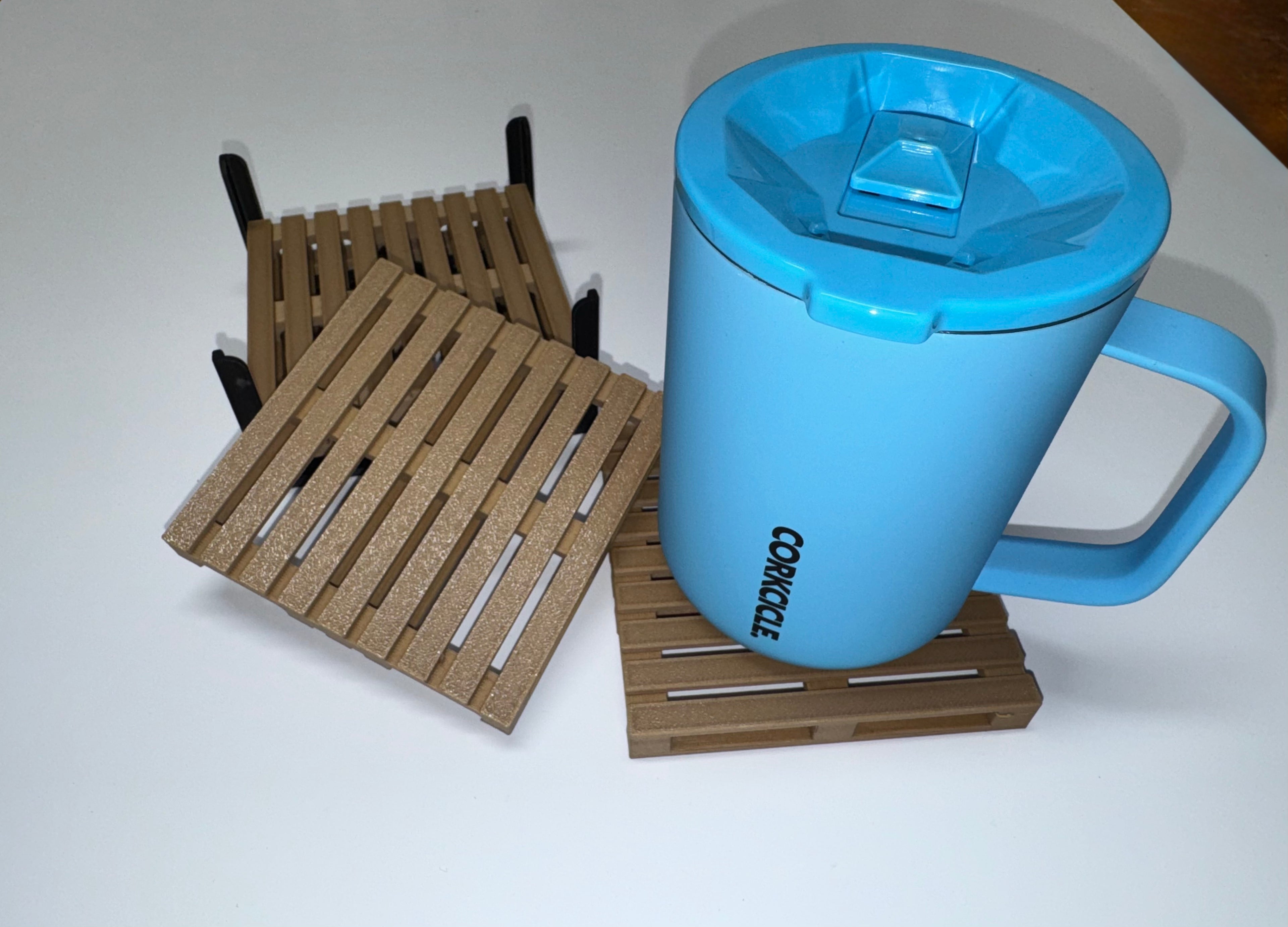 Two mini pallet coasters in brown and copper tones with black holder