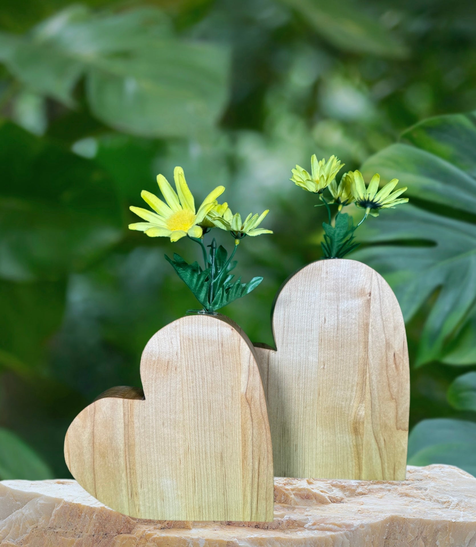 Single heart-shaped wooden vase with yellow flowers on a stone surface