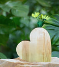 Pair of heart-shaped wooden vases with yellow flowers on a stone surface