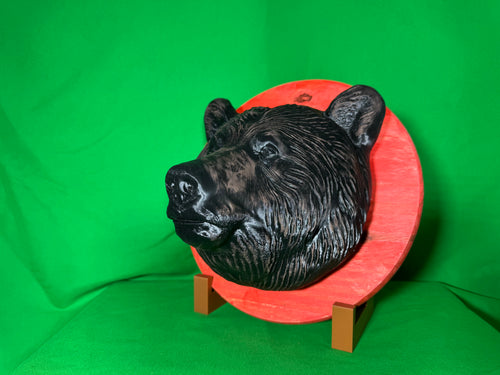 3D printed bear head wall hanging on red wooden round backplate, side view